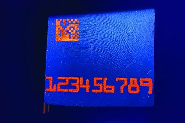 orange fluorescent numbers and QR code sample marks on a blue background. The marks are on the end of a square piece of lumber. Industrial printer ink, industrial inkjet ink, and industrial printing ink.